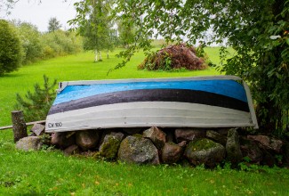 Eesti lipu värvides paat tõstetud tagurpidi murul olevale kivihunnikule